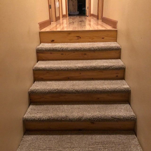 Brown carpet treads installed on white wooden stairs with a natural wood finish on the sides. (2)