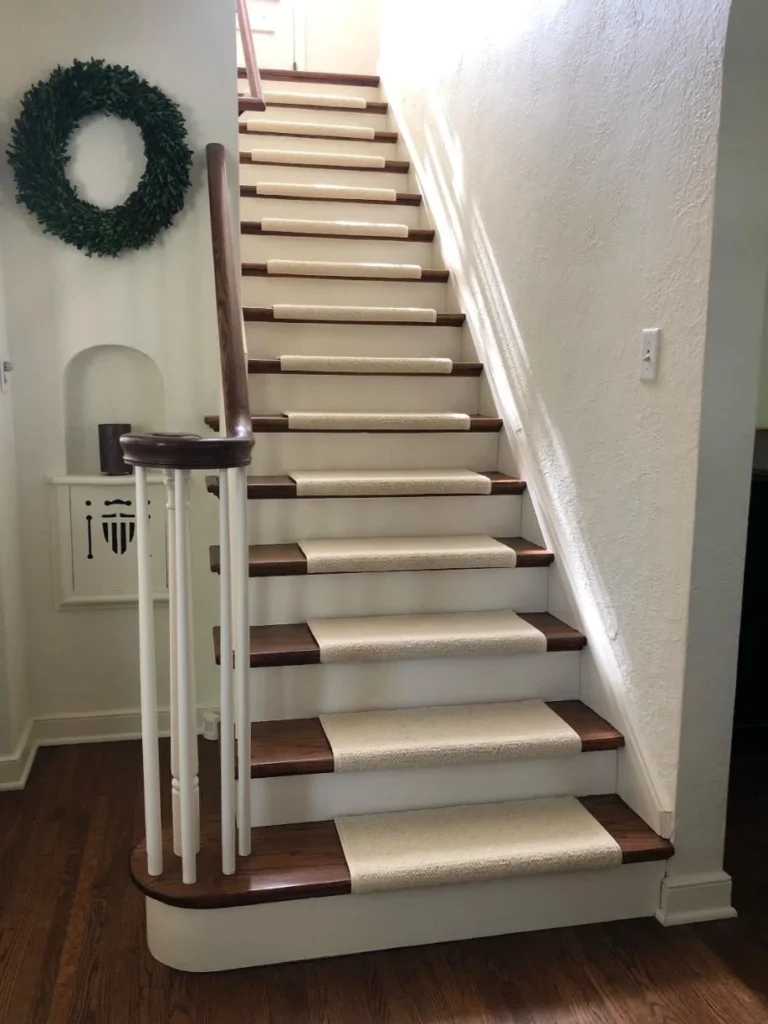 Off-white narrow carpet runners centered on dark wood stairs.