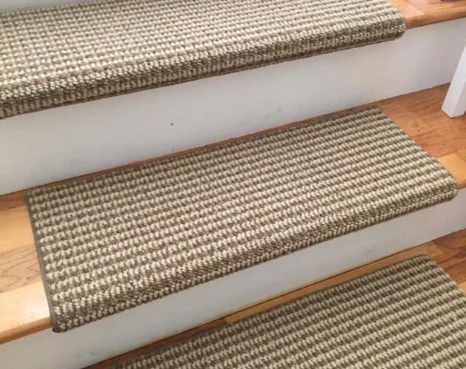Tan and white woven checkered stair treads on light wood steps.