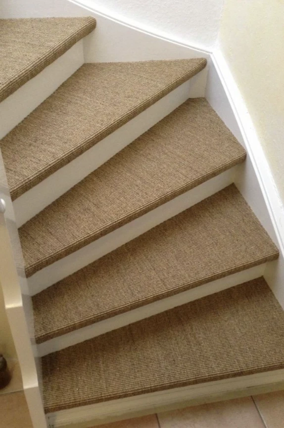 Woven natural fiber carpet treads custom-fitted to a winding staircase.