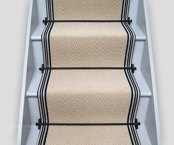 light beige herringbone-patterned sisal stair runner with dark navy blue striped borders.