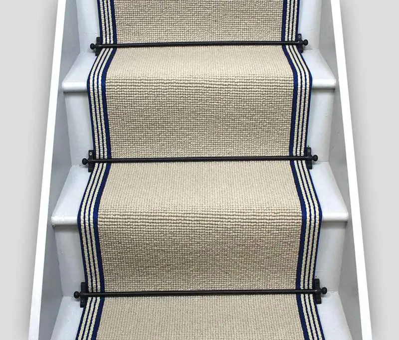 sisal-textured stair runner with navy blue striped borders on a white staircase.