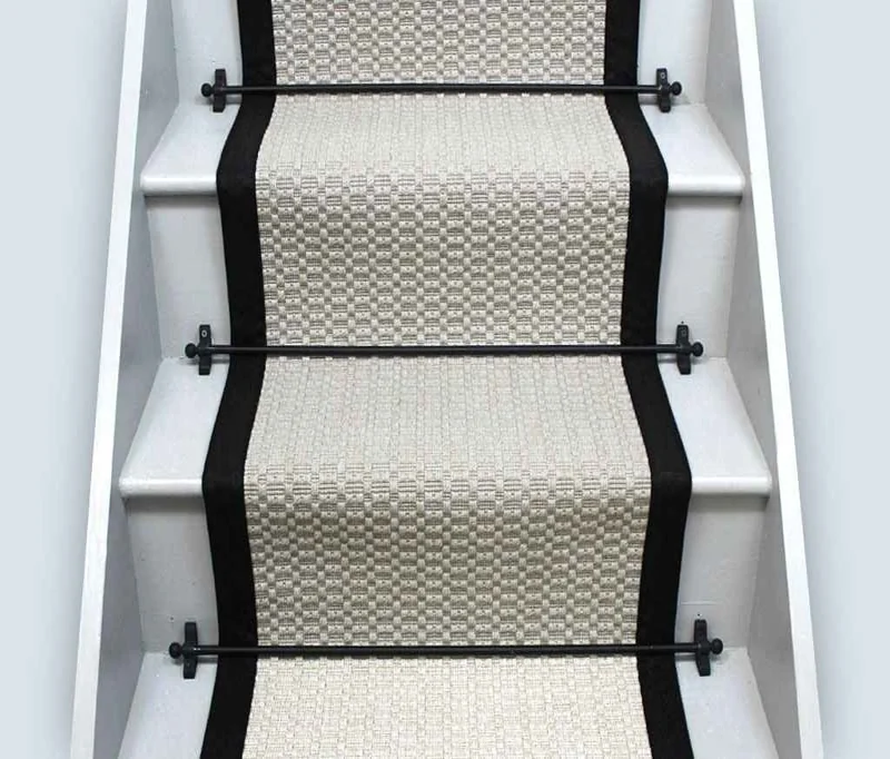 stairs featuring a woven, cream-colored sisal-style runner with a thick black fabric border.