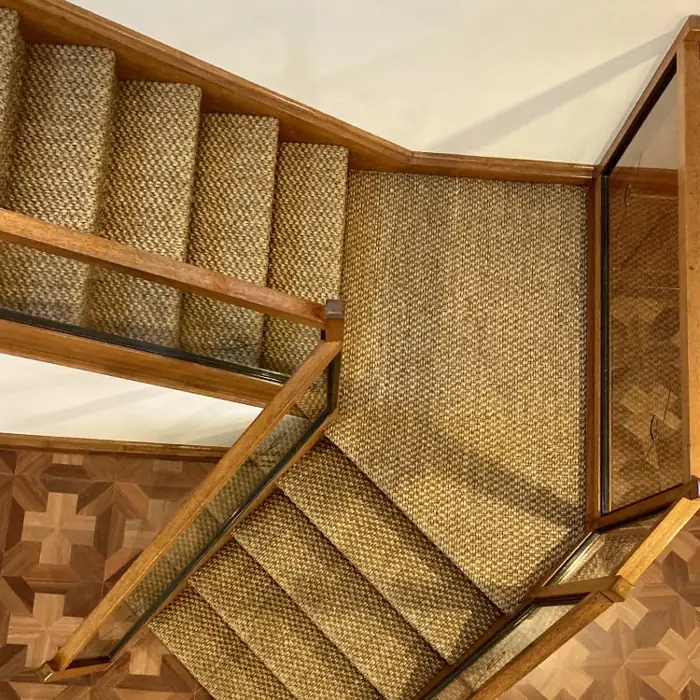 textured brown sisal carpet runner on the steps and landing, set against a geometric patterned wood floor.