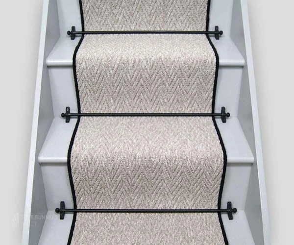 wooden stairs featuring a light beige herringbone-patterned sisal carpet runner