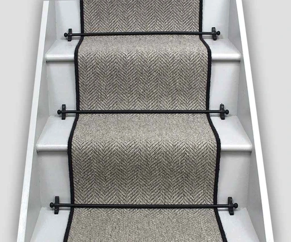 wooden stairs featuring a light grey herringbone-patterned wool carpet runner.