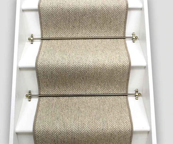wool carpet runner on white wooden stairs, held in place by elegant brass stair rods.