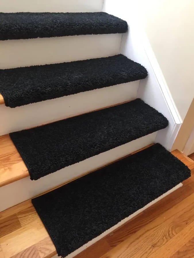 Black-plush-carpet-treads-with-wrap-around-edges-on-white-and-wood-stairs
