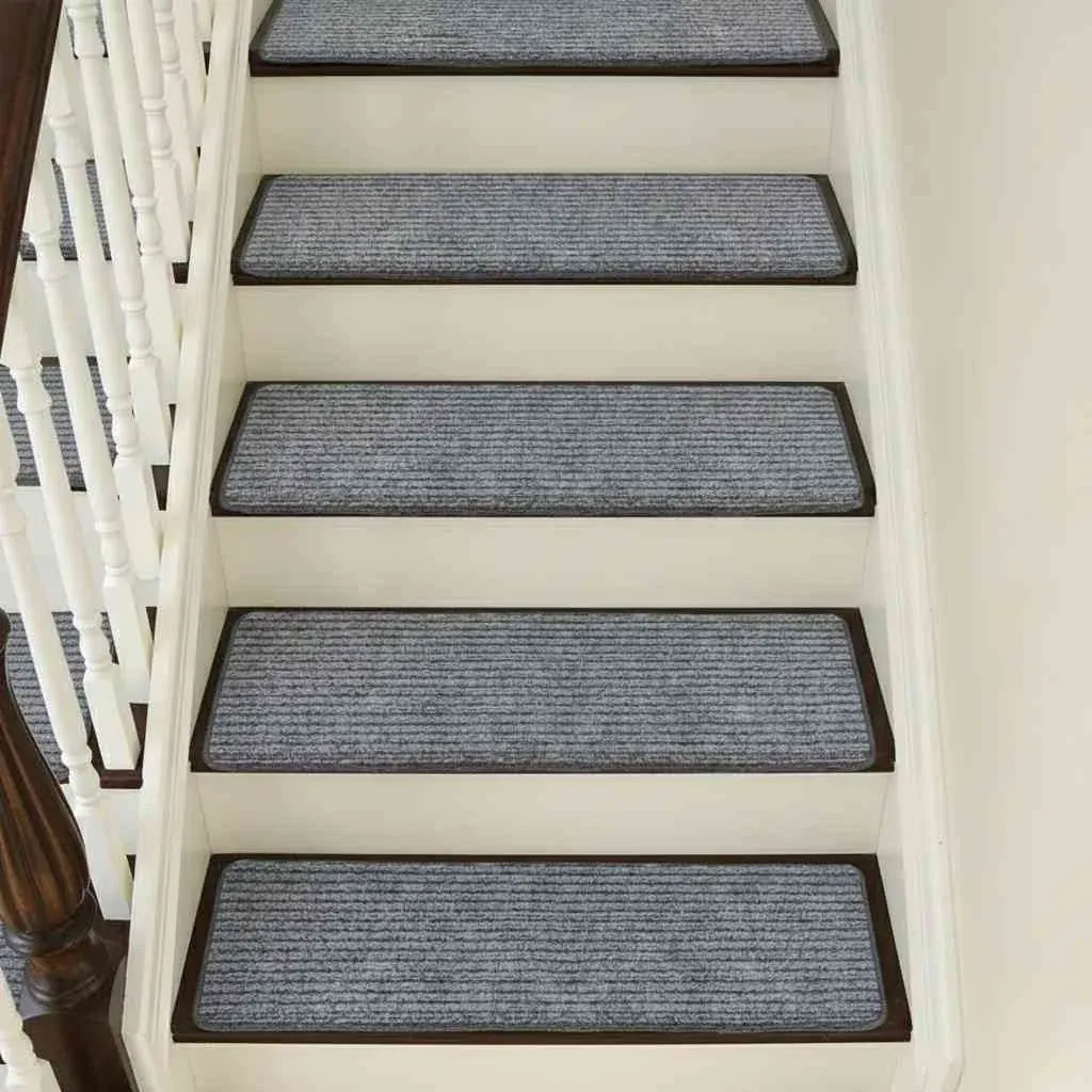 A straight view looking up a white wooden staircase, where each step is covered with a rectangular, gray ribbed carpet tread.