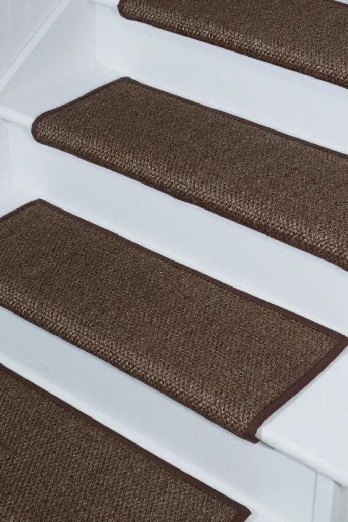 Textured brown sisal stair treads with dark borders on white stairs.